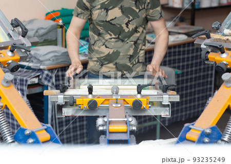 Worker printing picture application Serigraphy silk screen print process at clothes factory. Frame, squeegee and plastisol color paints. Worker printing picture application Serigraphy silk screen print process at clothes factory. Frame, squeegee and plastisol color paints. 93235249