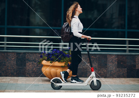 Young woman with electric scooter at the city. 93235272