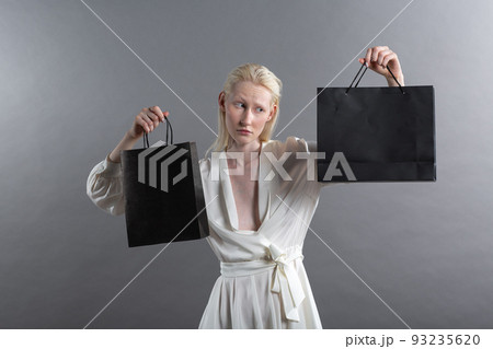 White caucasian albino blond woman holds shopping bag. Sale and discounts on market and Black Friday concept. 93235620