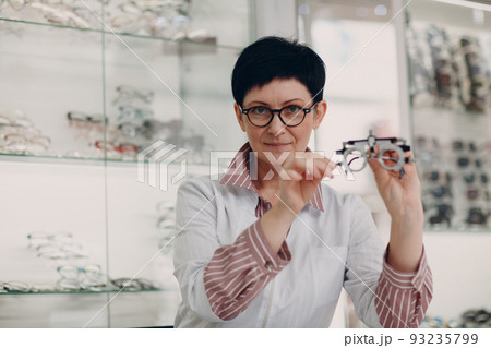 Happy Optician Choosing Eyeglasses, female optometrist with glasses. 93235799