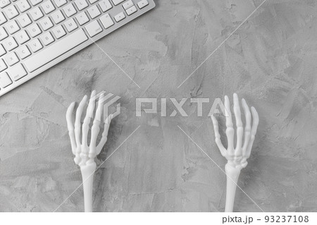 Halloween gray background with white skeleton hands and computer keyboard. Halloween holiday online shopping banner mockup. Top view, copy space Halloween gray background with white skeleton hands and computer keyboard. Halloween holiday online shopping banner mockup. Top view, copy space 93237108