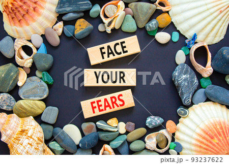 Face your fears and support symbol. Concept words Face your fears on wooden blocks. Beautiful black background. Sea stones and sea shells. Business and Face your fears quote concept. Copy space. 93237622