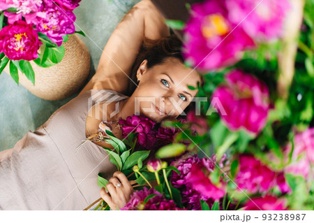 an attractive woman on the floor with a bouquet of peonies. 93238987