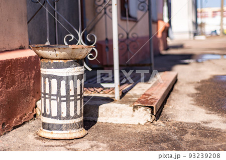 old rusty cracked urn stands near the porch 93239208