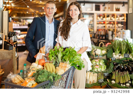 Glad couple is standing with cart with products in supermarket 93242998