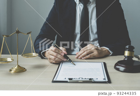 Lawyer hand holding pen and providing legal consult business dispute service at the office with justice scale and gavel hammer Lawyer hand holding pen and providing legal consult business dispute service at the office with justice scale and gavel hammer 93244335