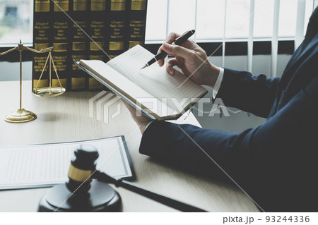 Lawyer hand holding pen and providing legal consult business dispute service at the office with justice scale and gavel hammer Lawyer hand holding pen and providing legal consult business dispute service at the office with justice scale and gavel hammer 93244336