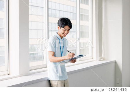 メモをする介護職員の男性 93244456