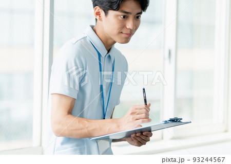 メモをする介護職員の男性 93244567
