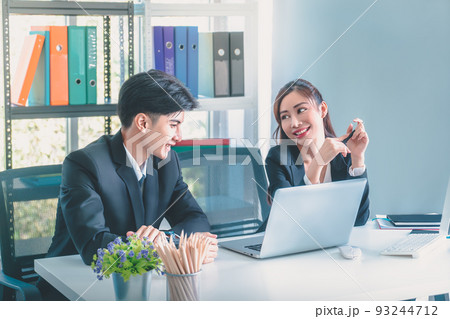 Asian office worker having a flirty conversation talk while working together with smile and laughing. Asian office worker having a flirty conversation talk while working together with smile and laughing. 93244712