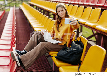 A girl on the seats in the school stands takes a selfie and prepares for classes 93245962