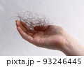 長い抜け毛を持つ女性の手 93246445