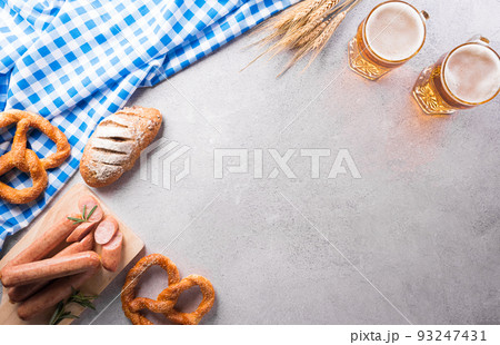 Oktoberfest festival decoration symbols made from Pretzel loaf, beer, sausage, potato chips and Bavarian white and blue fabric on stone background. 93247431