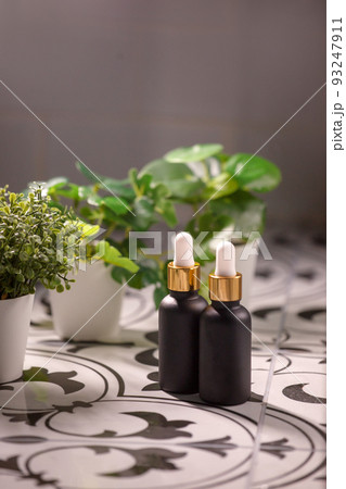 Serum, oil, lotion in amber matt brown dropper bottle in front, glass with water drops and green leaves, bathroom. Spa product. Organic, bio, natural cosmetic. Beauty, skincare concept. Serum, oil, lotion in amber matt brown dropper bottle in front, glass with water drops and green leaves, bathroom. Spa product. Organic, bio, natural cosmetic. Beauty, skincare concept. 93247911