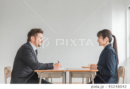 学校で二者面談を行う教師とアジア人の高校生 93248042
