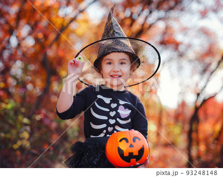 Young girl in black costume goes trick or treating 93248148