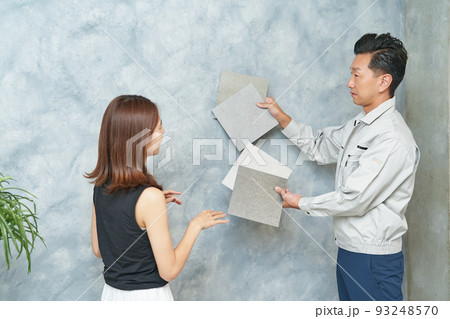 業者に壁材を相談する女性 93248570