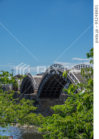 快晴の青空のもと 木々の間に美しい太鼓橋 93248601