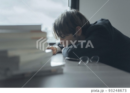 机に突っ伏すハーフ男性 93248673