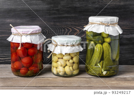 Homemade pickled cherry tomatoes, cucumbers, champignons, garlic, eggplant, red peppers in jars on wooden shelf Homemade canned and fermented foods concept Seasonal product. Homemade pickled cherry tomatoes, cucumbers, champignons, garlic, eggplant, red peppers in jars on wooden shelf Homemade canned and fermented foods concept Seasonal product. 93249217