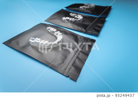 Invisible orthodontic cosmetic brackets aligners on a blue background lie on personal storage bags. Aligners for a beautiful smile. 93249437