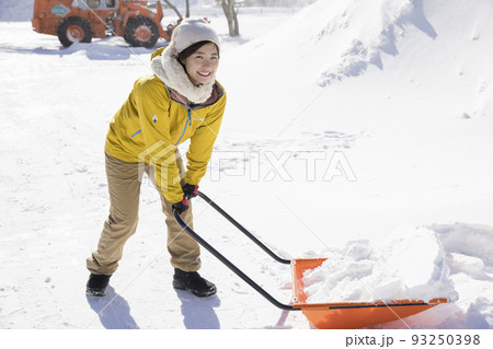 吹雪の中雪かきをする若い女性　除雪イメージ　スノーダンプ 93250398