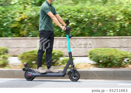 電動キックボードで走行する男性 93251663
