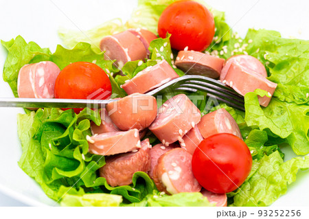 Close up of fresh mixed salad with wurstel in a bowl. Raw salad on white background. Close up of fresh mixed salad with wurstel in a bowl. Raw salad on white background. 93252256