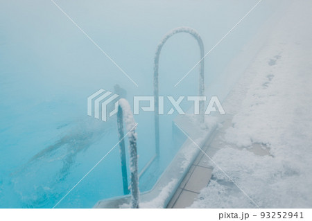 Fit swimmer male training swim in open winter swimming pool with fog. Geothermal outdoor spa health concept. 93252941