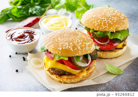 A delicious fresh homemade hamburger on a slate or stone table. Cheeseburger with meat cutlet and vegetables. Street food, fast food. A delicious fresh homemade hamburger on a slate or stone table. Cheeseburger with meat cutlet and vegetables. Street food, fast food. 93260812