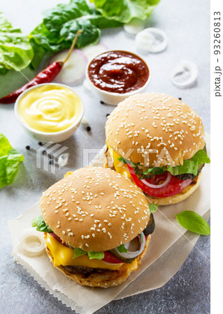A delicious fresh homemade hamburger on a slate or stone table. Cheeseburger with meat cutlet and vegetables. Street food, fast food. A delicious fresh homemade hamburger on a slate or stone table. Cheeseburger with meat cutlet and vegetables. Street food, fast food. 93260813