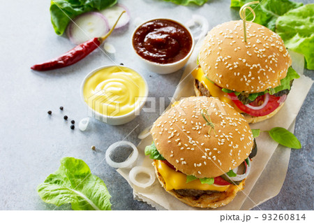 A delicious fresh homemade hamburger on a slate or stone table. Cheeseburger with meat cutlet and vegetables. Street food, fast food. A delicious fresh homemade hamburger on a slate or stone table. Cheeseburger with meat cutlet and vegetables. Street food, fast food. 93260814