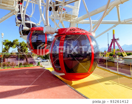 on the Ferris wheel there are large cabins for skiing tourists of red color with black, tinted windows to protect from the sun's rays. boarding tourists on the Ferris wheel there are large cabins for skiing tourists of red color with black, tinted windows to protect from the sun's rays. boarding tourists 93261412