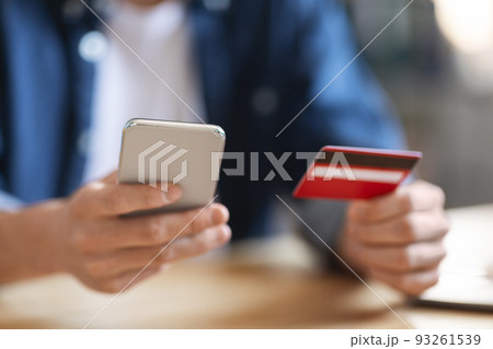 E-Commerce Concept. Closeup Shot Of Unrecognizable Male Using Smartphone And Credit Card E-Commerce Concept. Closeup Shot Of Unrecognizable Male Using Smartphone And Credit Card 93261539