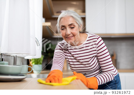 Portrait Of Beautiful Senior Housewife Washing Table In Kitchen With Rag Portrait Of Beautiful Senior Housewife Washing Table In Kitchen With Rag 93261972