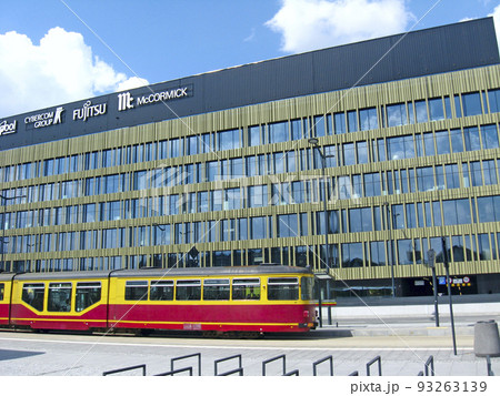 Modern tram riding around city. Red tram going on city street in Lodz. City transport. Modern tramway going along town. City tram on modern building background 93263139