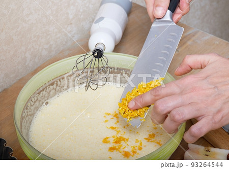 Process of making the handmade home stile delicious golden apple pie.Close-up hands view above the structure craft wooden surface of the table. Lemon lemon peel on the knife. 93264544