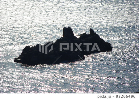 福井県坂井市三国　東尋坊からみた海面にシルエットになった戦艦のような岩 93266496