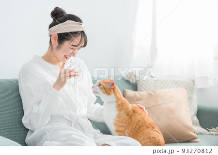 家・猫カフェで猫におやつをあげる日本人女性（餌） 93270812