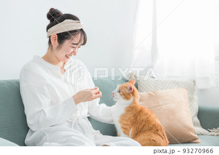 猫におやつをあげる日本人女性（餌） 93270966