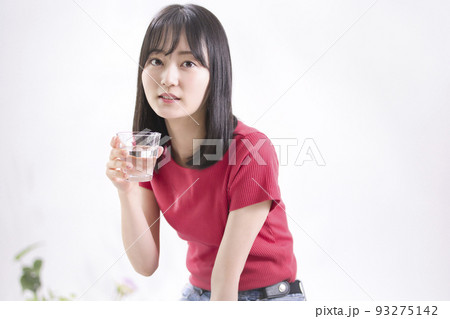 水の入ったグラスを持つ笑顔の若い女性 水の入ったグラスを持つ笑顔の若い女性 93275142