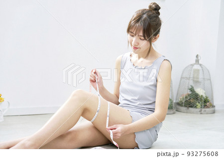 自宅でメジャーで太ももを測る女性 自宅でメジャーで太ももを測る女性 93275608