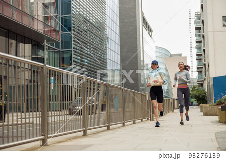 Two athletic women in sportswear are running around the city. Reaching the goal 93276139
