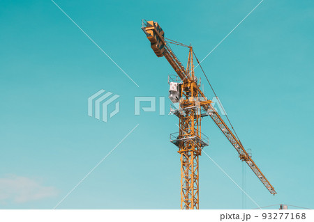Tower Crane lattice boom hook clear blue sky sun background. Construction site work building installation 93277168