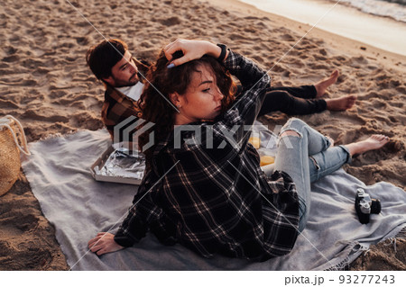 Young couple having picnic on the beach at dawn, woman and man meeting sunrise together on the sea 93277243