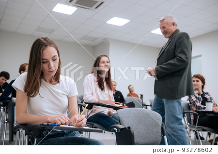 An elderly teacher at a technical university conducts a lecture for first-year students in the college auditorium An elderly teacher at a technical university conducts a lecture for first-year students in the college auditorium 93278602