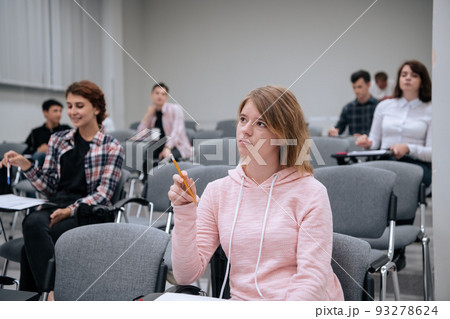 College students listen attentively to the professors lecture, sitting on chairs in a large audience College students listen attentively to the professors lecture, sitting on chairs in a large audience 93278624