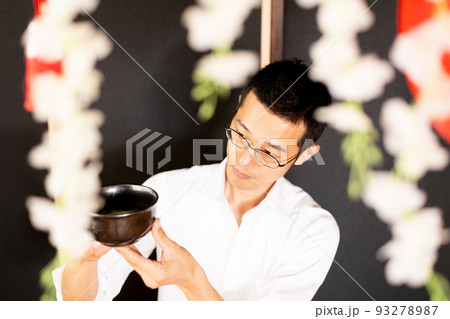 抹茶用のお茶碗の模様を肩の高さで眺める男性 93278987