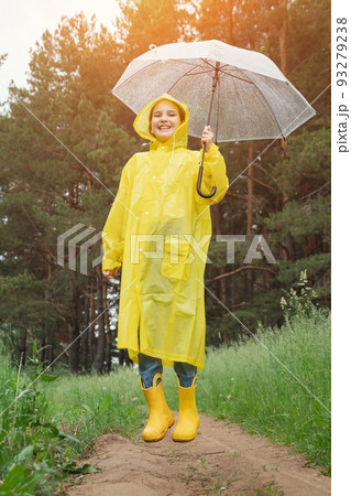 Cheerful girl in yellow raincoat jumps high spreading hands 93279238