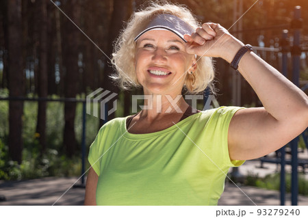 Mature woman in white cap looks at sun smiling closeup Mature woman in white cap looks at sun smiling closeup 93279240